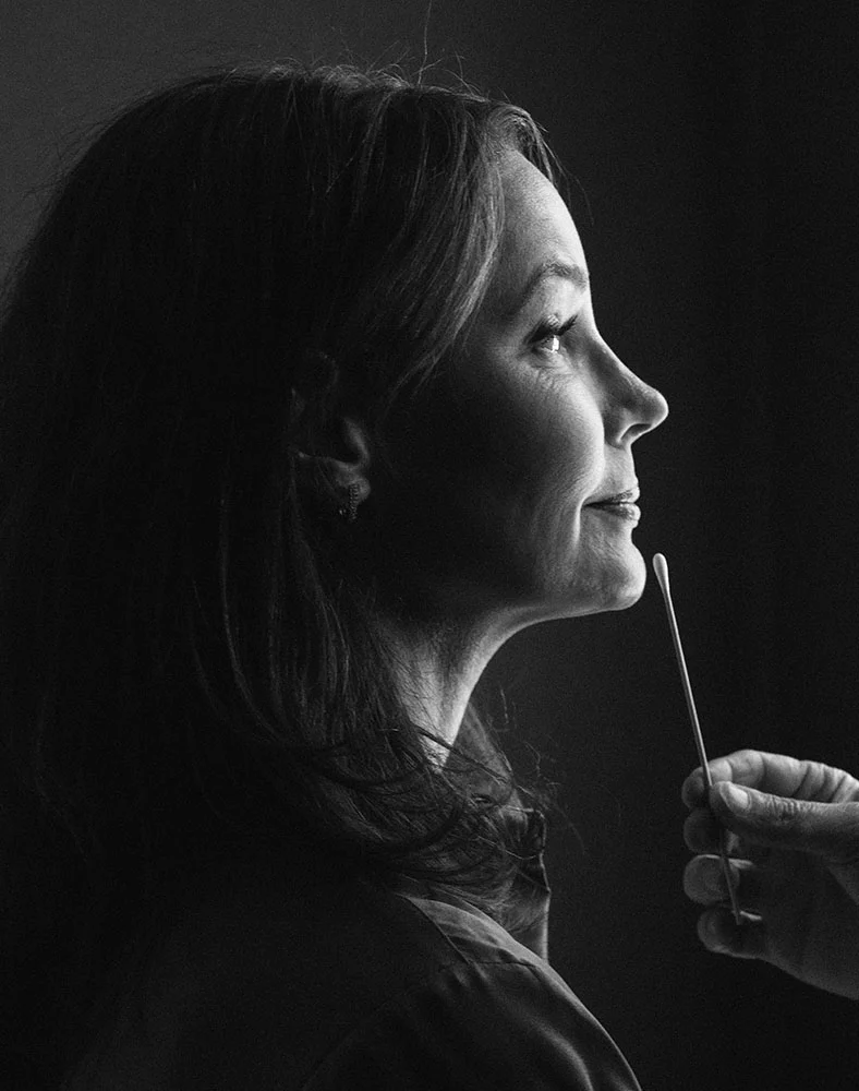 A black and white profile shot of a woman receiving a nasal swab test. The persons face in is in profile view, with a gentle expression. The swab is visible, held by a slightly visible hand - Chin Implant Augmentation in Carmel, IN